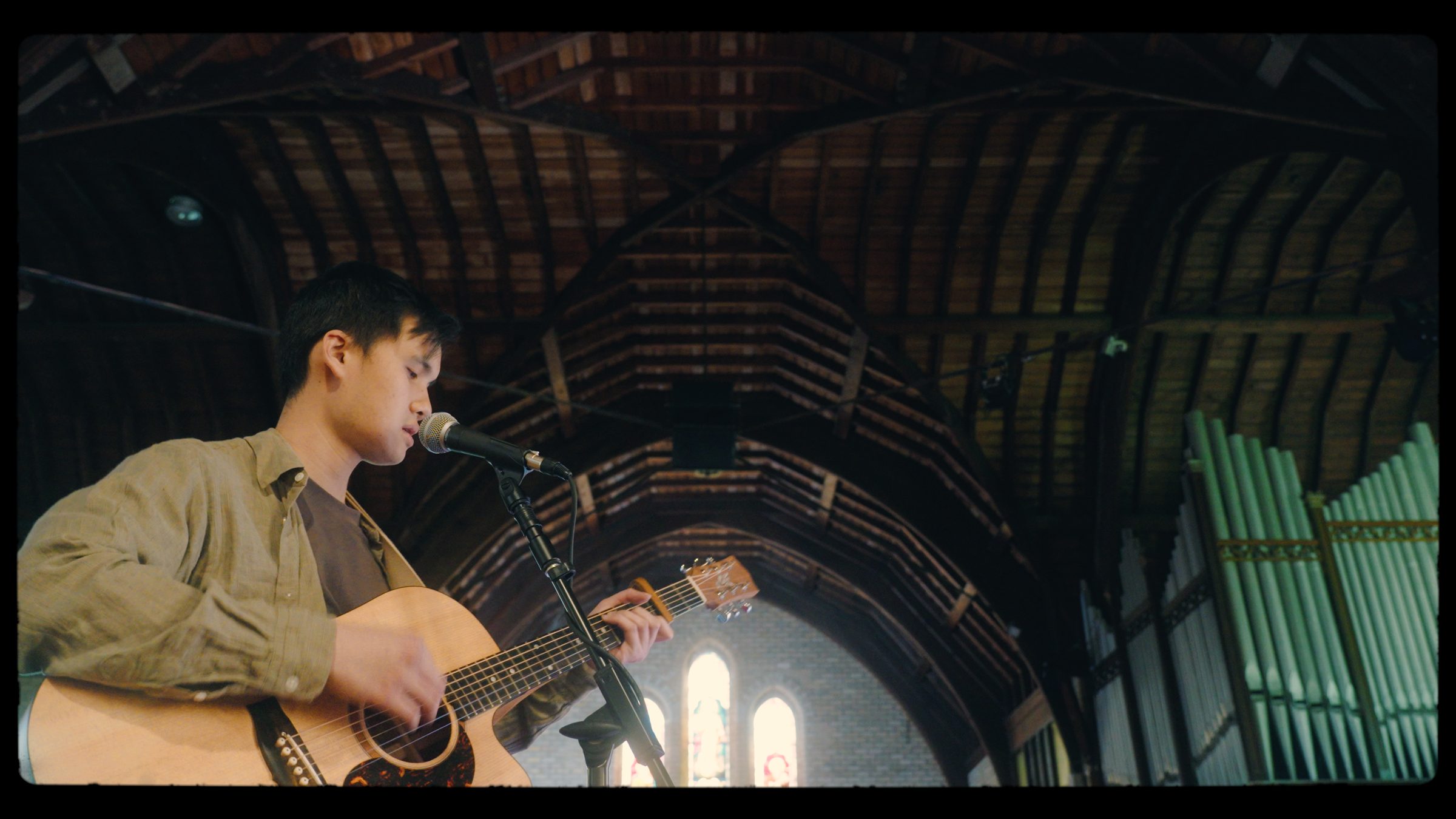 Daniel Chin singing Eternal Word beneath the timber roof of a church