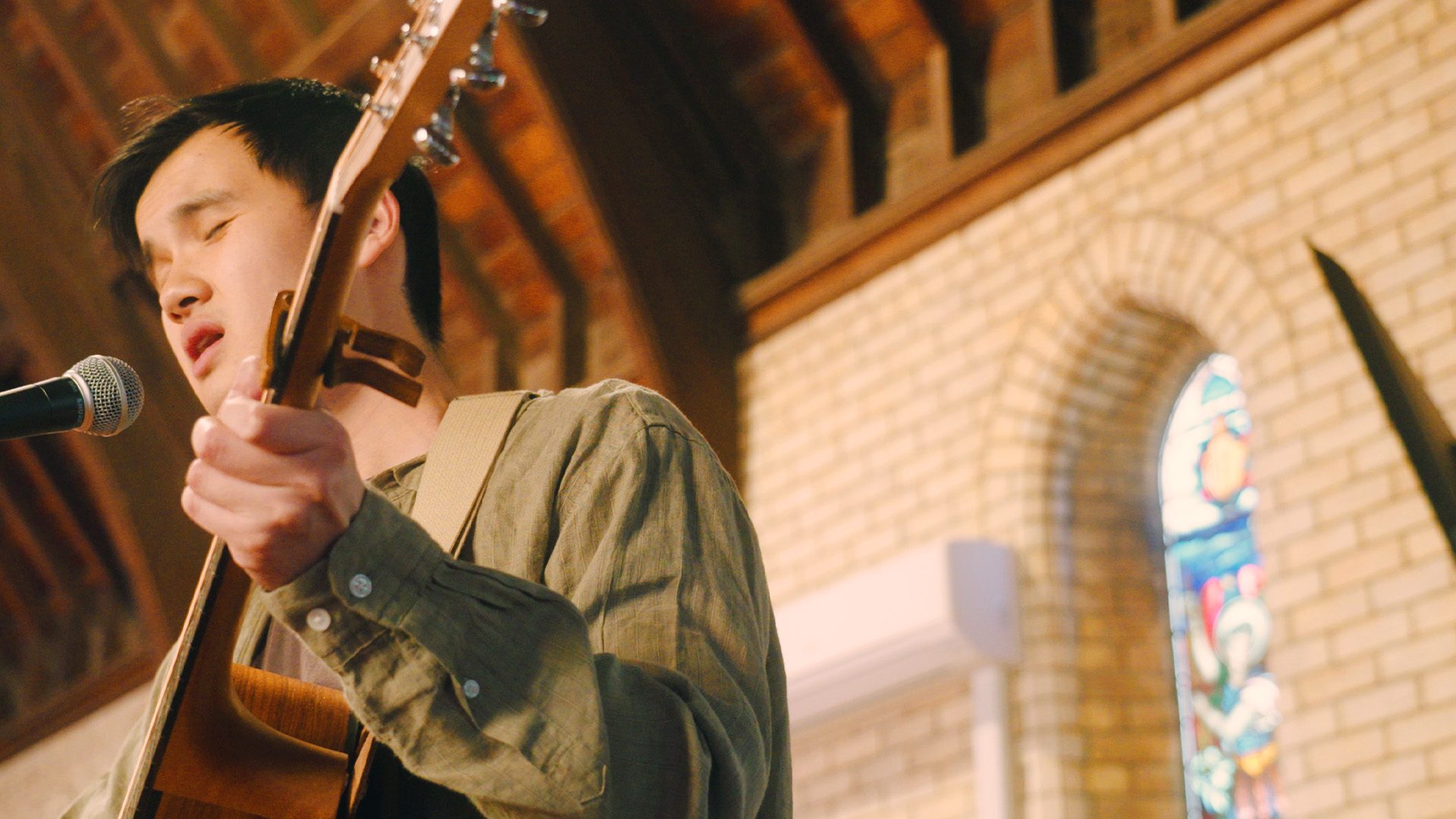 Daniel Chin singing with his guitar inside a church